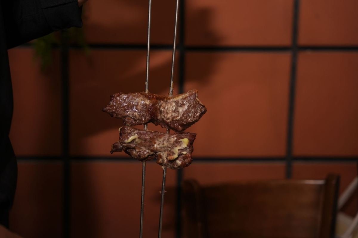 Pieces of beef on a long skewer, ready to be carved for churrasco at Brasa