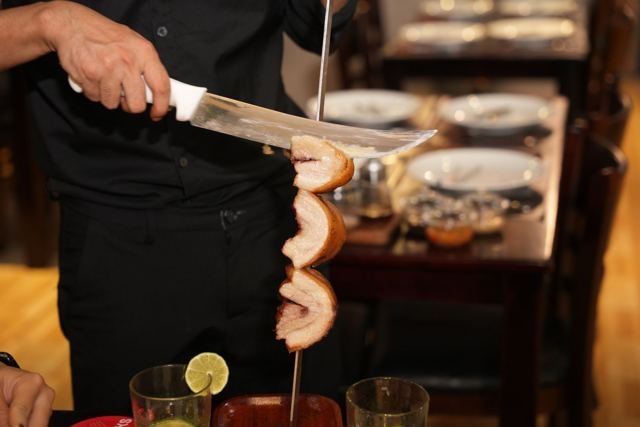 A passador carving sausage during Brazilian BBQ service at Brasa