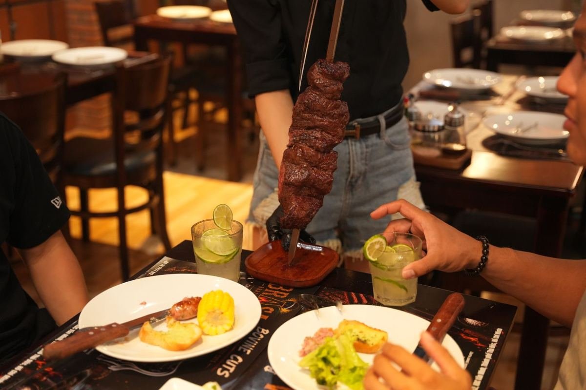 A skewer of grilled beef being served at the table at Brasa Brazilian BBQ