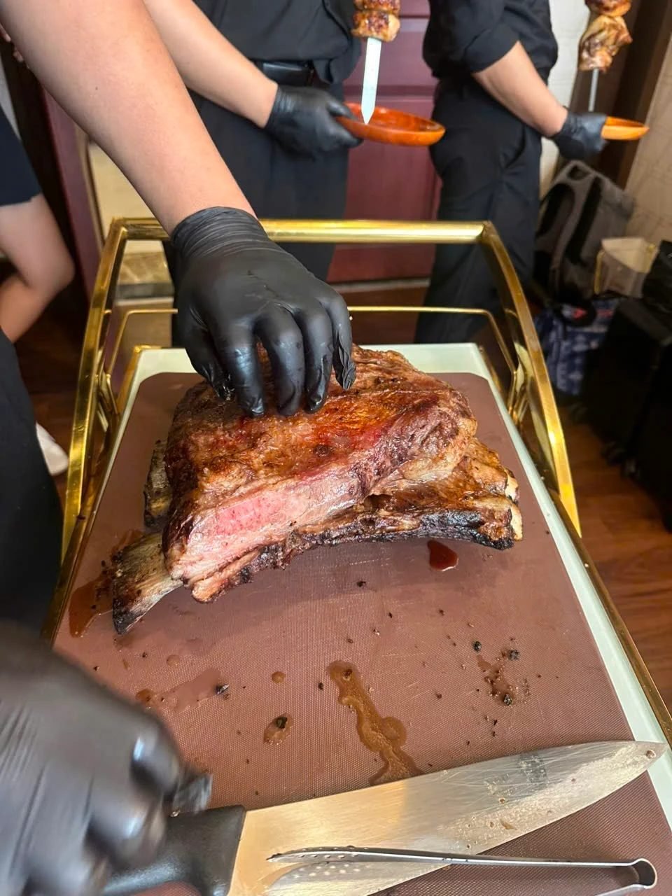 A Brasa passador with a fire-roasted beef rib, ready to carve